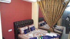 A bedroom with a tufted headboard, patterned bedspread, and a large mirror reflecting the room. - Ghazrin's Classic Hotel (Johor Bahru)