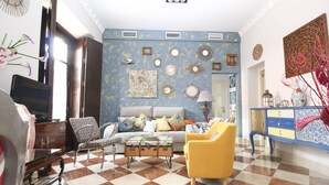 A living room with a checkered floor, a sofa, a yellow armchair, and a vintage trunk as a coffee table. - OFFER, ELEGANCE AND COMFORT, A DREAM IN THE CENTER OF SEVILLE (Sevilla)