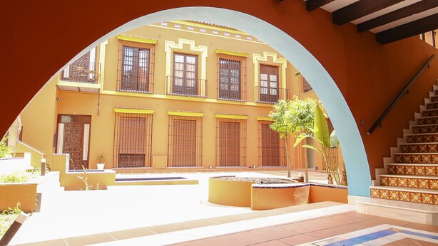 A courtyard with a tiled floor, a staircase, and a building with barred windows. - OFFER, ELEGANCE AND COMFORT, A DREAM IN THE CENTER OF SEVILLE (Sevilla)