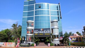 A modern hotel with a glass facade, a prominent sign for 'Tiffin Meals Biriyani', and a staircase leading to the entrance.