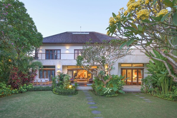 A modern house with a well-maintained garden, a patio with seating, and a large window overlooking the garden. - Villa Kaira (Canggu)