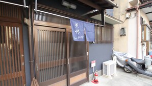 A traditional Japanese building with a sliding door, a covered scooter, and a fire extinguisher. - Kyoto Kyo-Hiiragi (Kyoto)