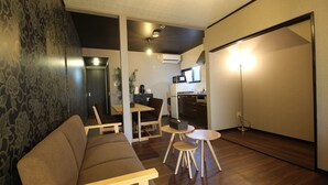 A living room with a sofa, a dining table, and a kitchen area in the background. - Kyoto Kyo-Hiiragi (Kyoto)