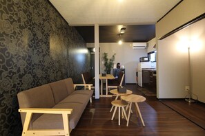 A modern living room with a sofa, wooden coffee table, and chairs. A kitchen is visible in the background. - Kyoto Kyo-Hiiragi (Kyoto)