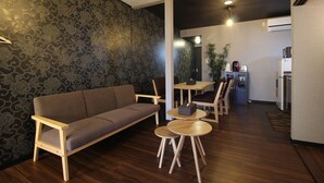 A modern living room with a sofa, two small wooden tables, and a dining area with chairs. - Kyoto Kyo-Hiiragi (Kyoto)