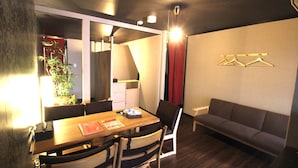 A modern room with a dining table, chairs, a sofa, and a wall-mounted clothing rack. - Kyoto Kyo-Tsubaki (Kyoto)