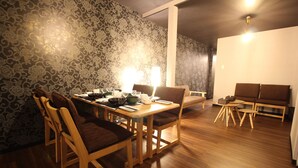 A dining area with a wooden table and chairs, a patterned wallpaper, and a wooden floor. - Kyoto Kyo-Tsubaki (Kyoto)