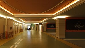 Un largo pasillo bien iluminado con diseño moderno, que incluye un candelabro y un cuadro grande en la pared derecha.