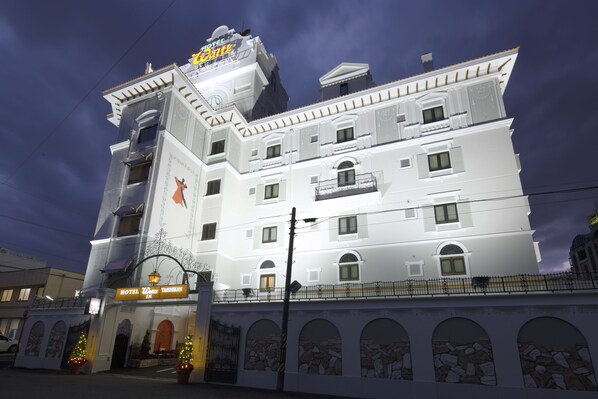 Un hotel de varios pisos con un estilo arquitectónico clásico, con balcones, ventanas de arco y una entrada destacada con un letrero.