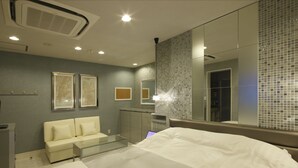 Una habitación de hotel moderna con una cama, una mesa de centro de vidrio, un sofá y un espejo grande.