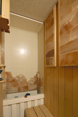 Un baño con bañera, paneles de madera y pared de azulejos.