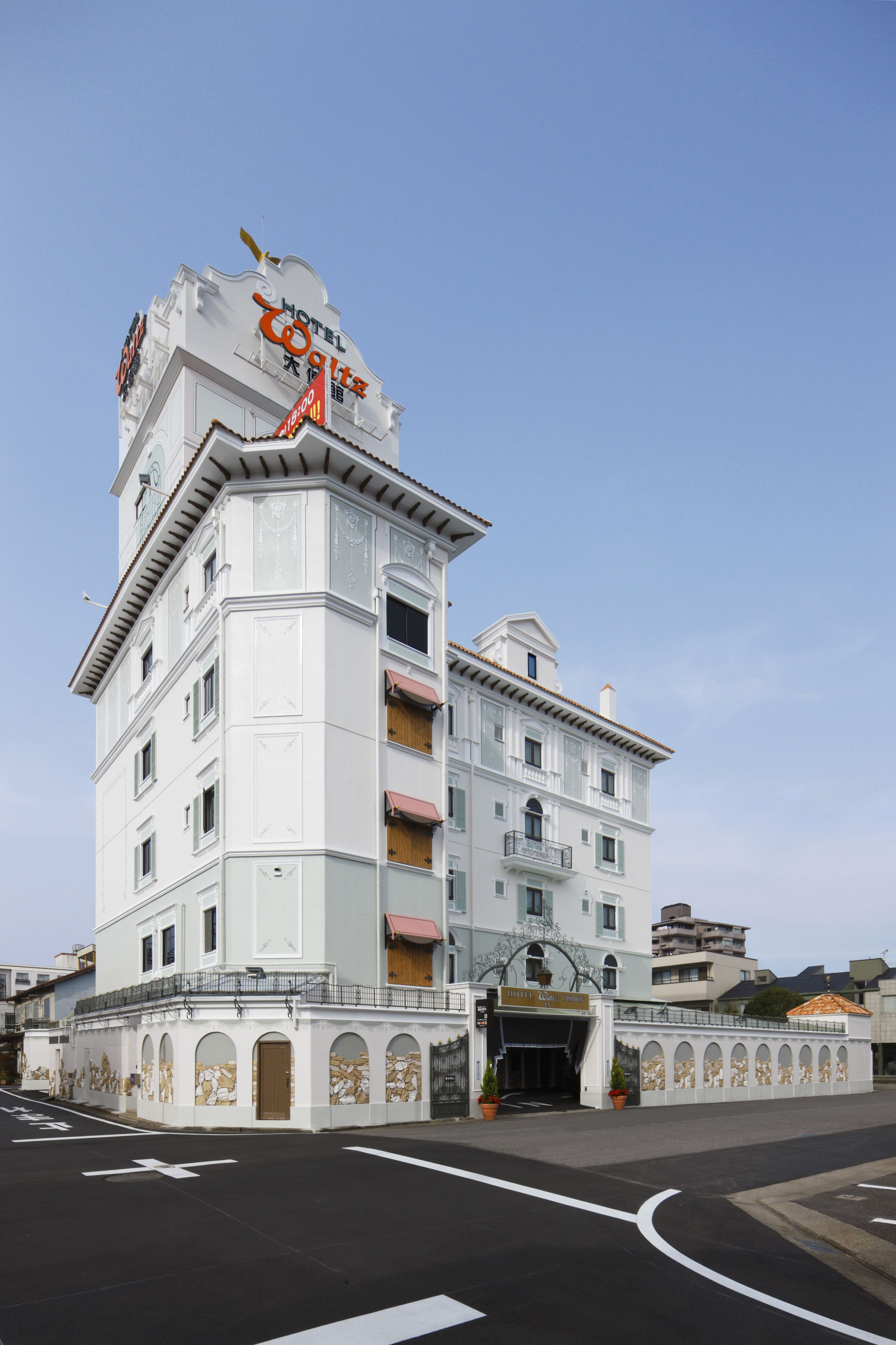 Et hotel med hvid facade, flere balkoner og en markant indgang.