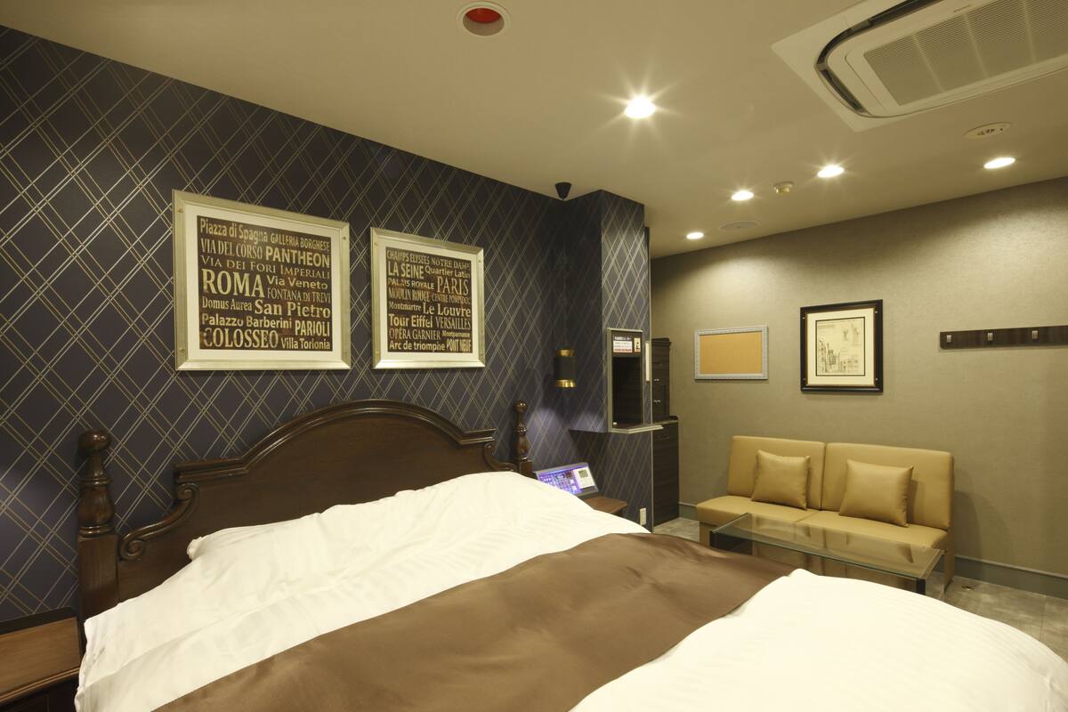 Habitación de hotel con cama, sofá y pared decorada con textos enmarcados.