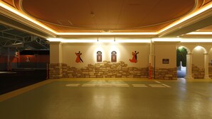 Un hall espacioso con techo alto, paredes de piedra y dos ventanas de arco.