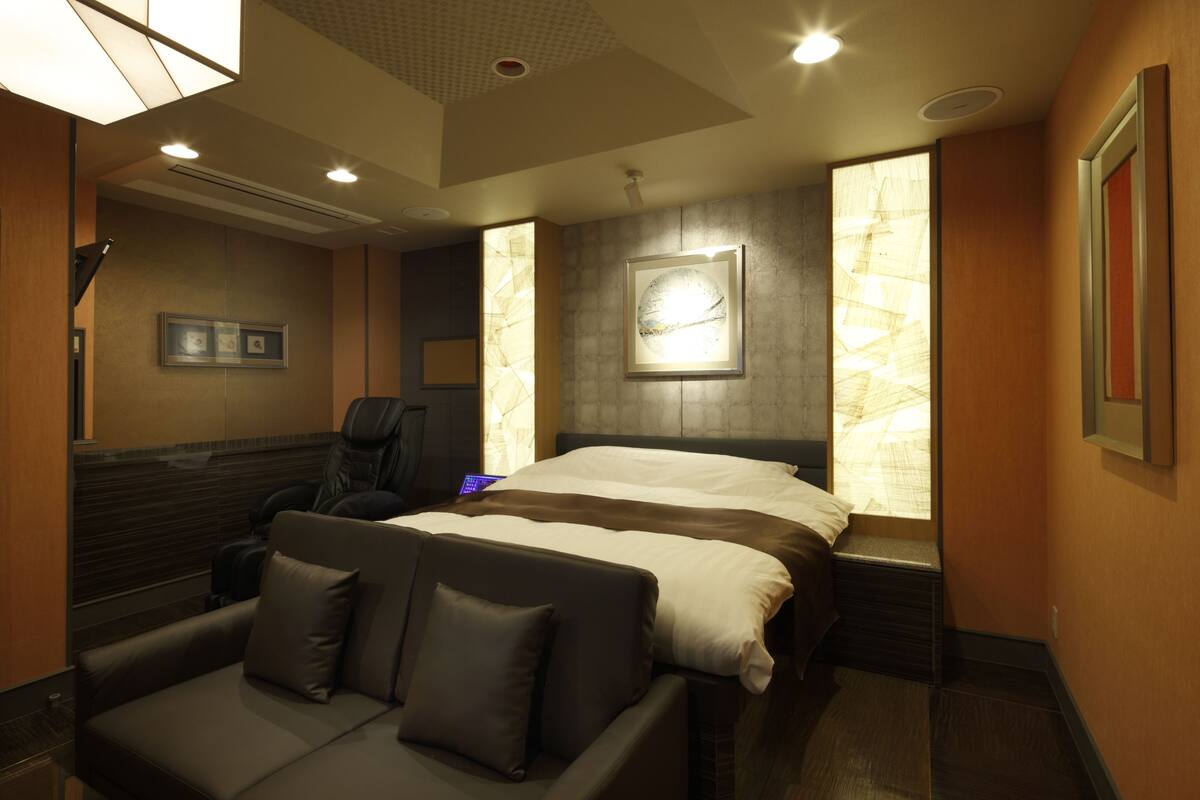 Una habitación de hotel con una cama, un sofá y un escritorio con una silla.