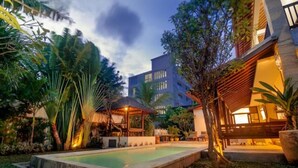 Um hotel moderno com piscina, vegetação exuberante e área externa bem iluminada.