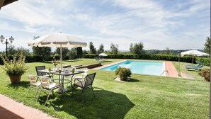 A backyard with a swimming pool, a dining table with chairs, and umbrellas. - Super panoramic, private pool, fast Wifi, Air cond, close to town - NO BILLS (Pisa)