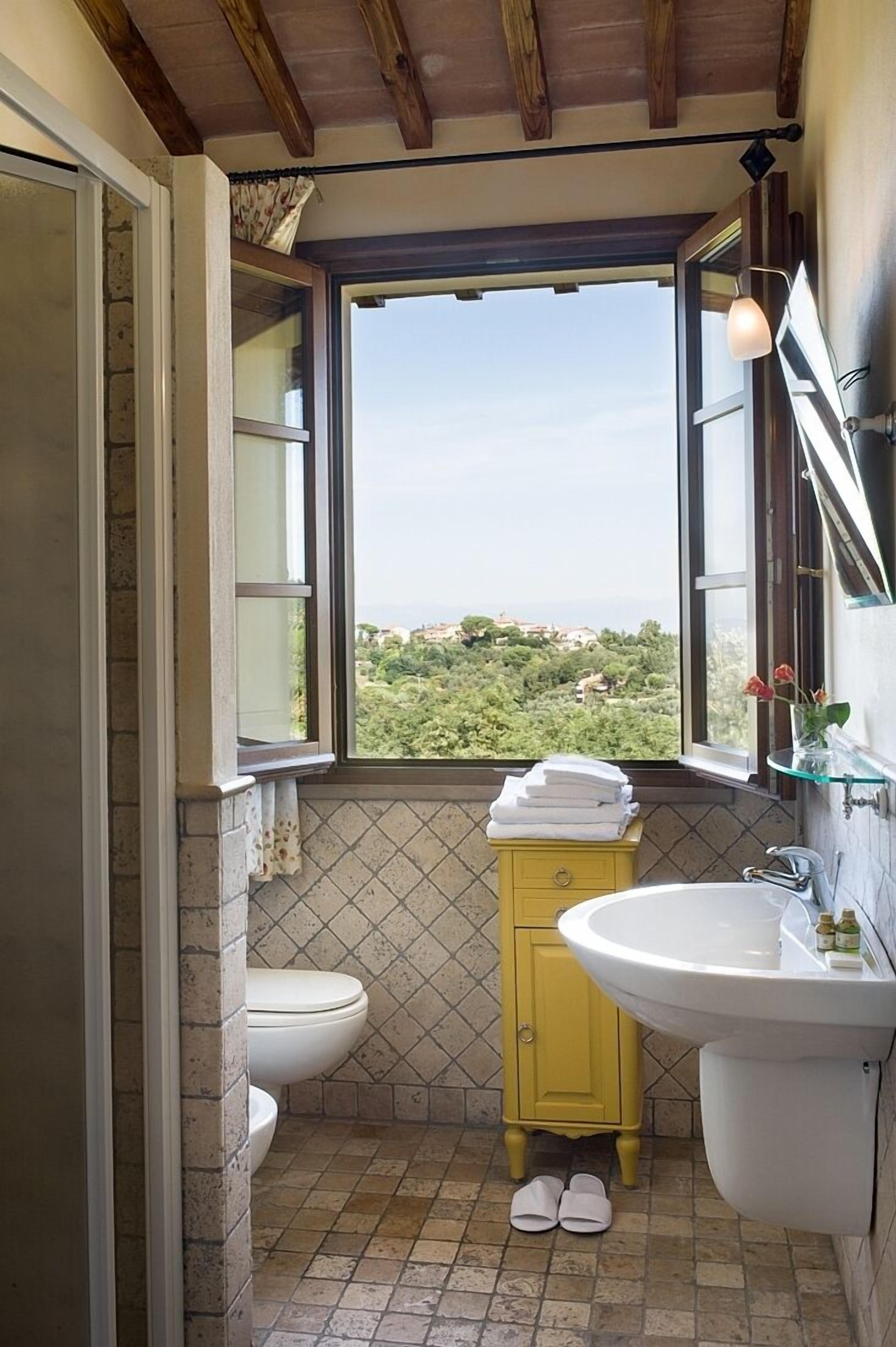 A bathroom with a toilet, yellow cabinet, and sink.