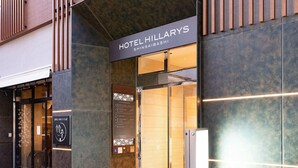 Exterior del Hotel Hillarys, con una fachada moderna, una entrada visible y un letrero que indica el nombre y la ubicación.