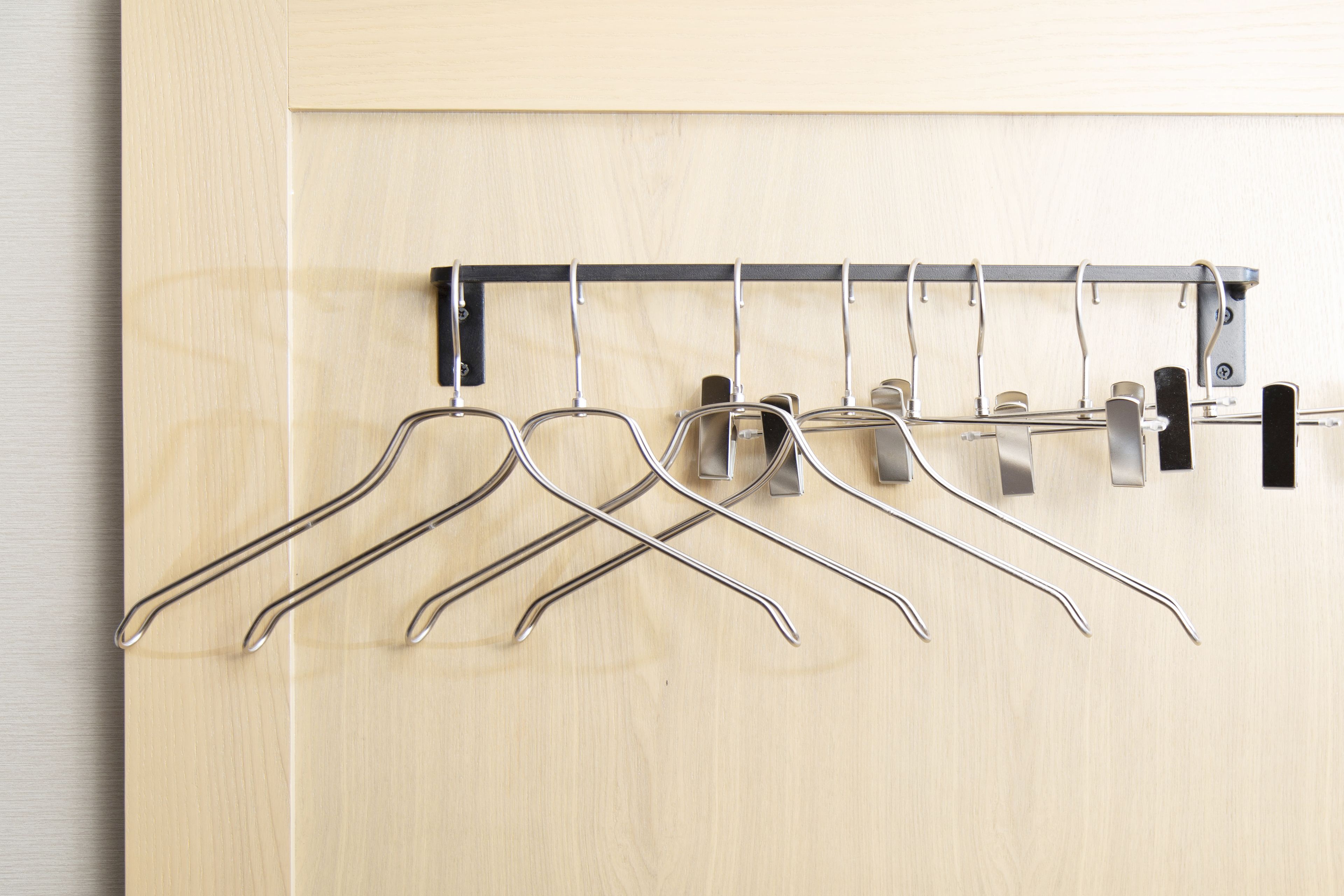 Une porte en bois avec un porte-manteau en métal sur lequel sont accrochés plusieurs cintres en métal.