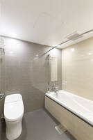 A modern bathroom with a toilet, a shower, and a bathtub.