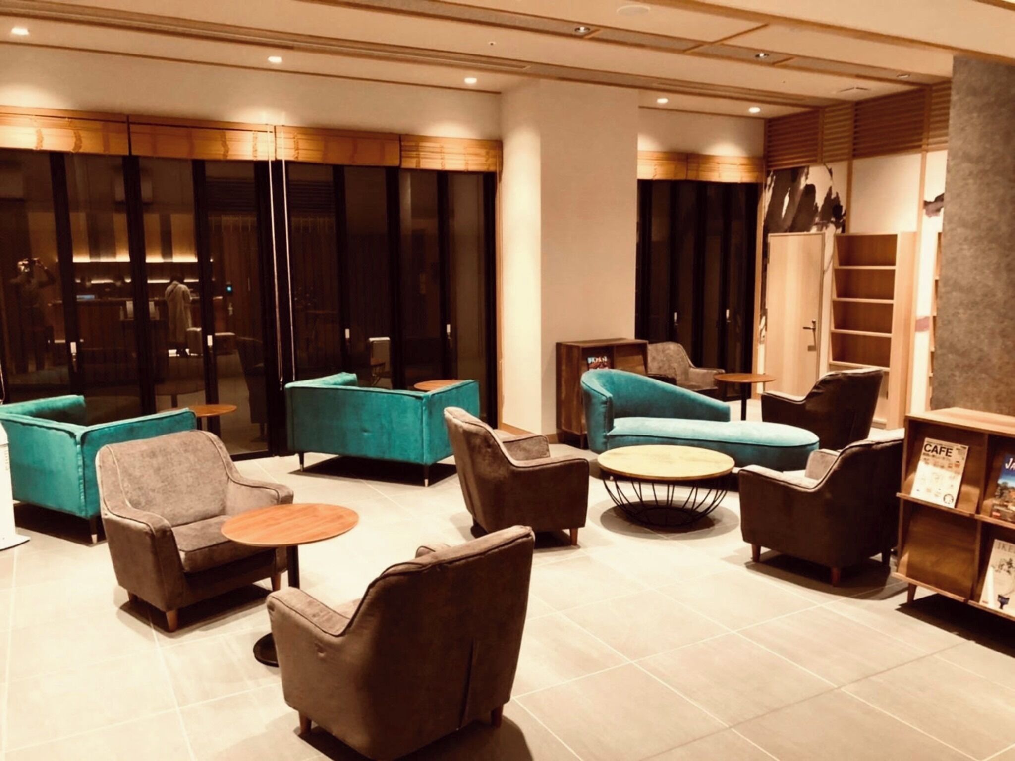 Et moderne loungeområde med sofaer, lænestole og et sofabord, med glasvæg og træpaneler.