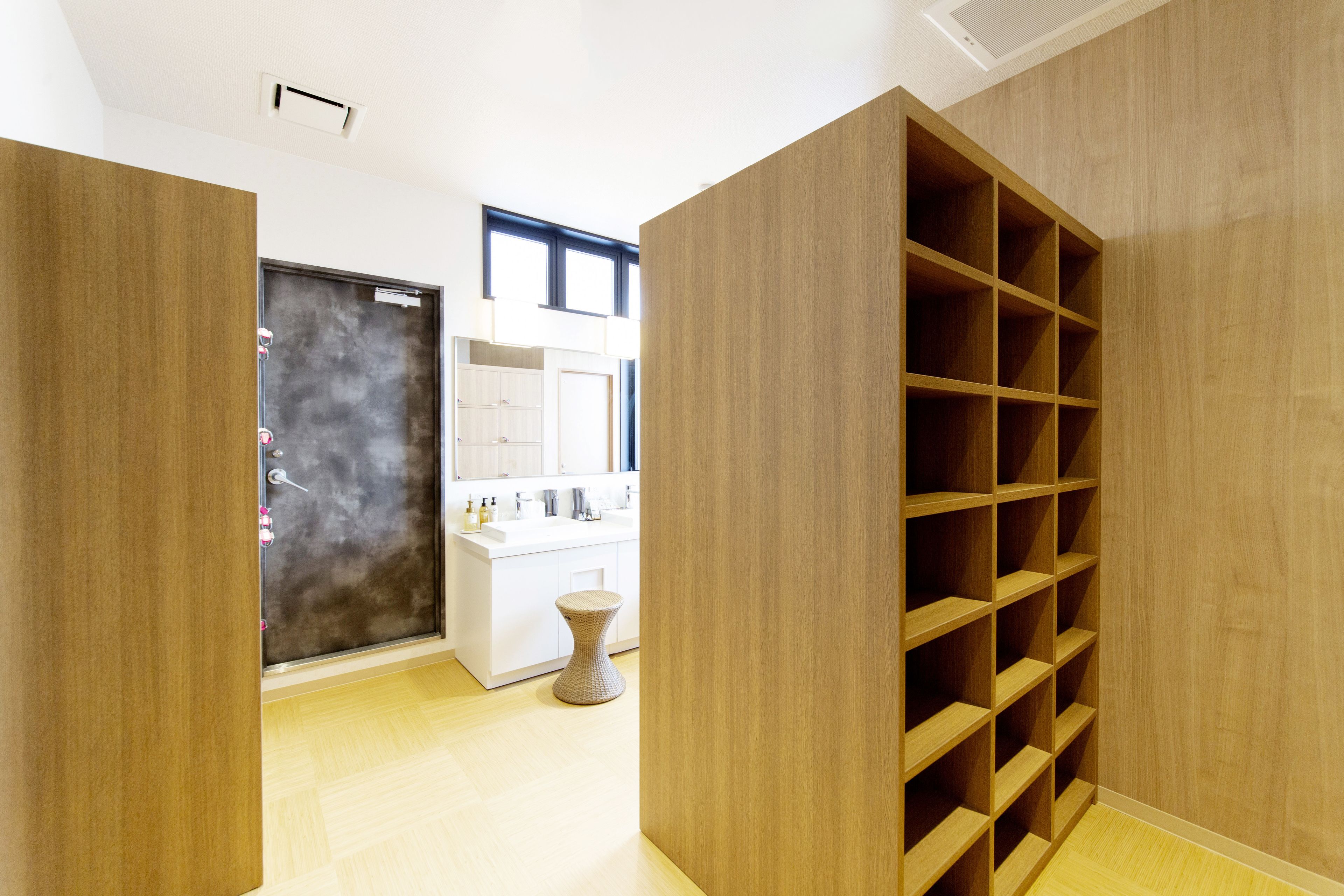 Un baño moderno con un tocador de madera, un taburete pequeño y un amplio estante de madera.