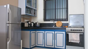 A compact kitchen with a refrigerator, microwave, stove, and sink.