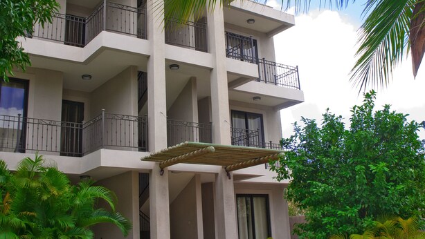A multi-story building with balconies, a swimming pool, and surrounding greenery.