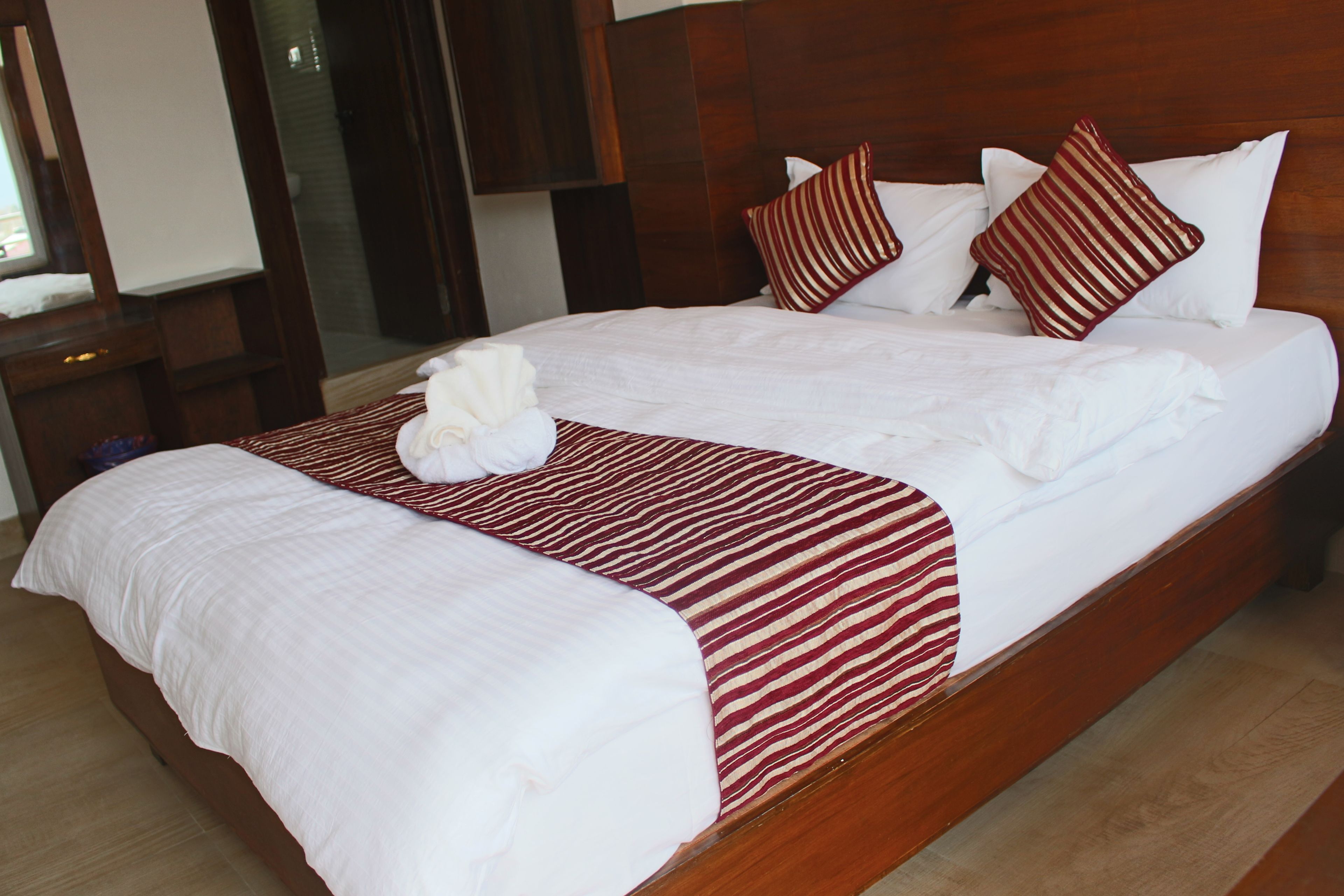 Ein großes Bett mit weißen Leinentüchern, einer rot-weißen gestreiften Decke und mehreren Kissen.