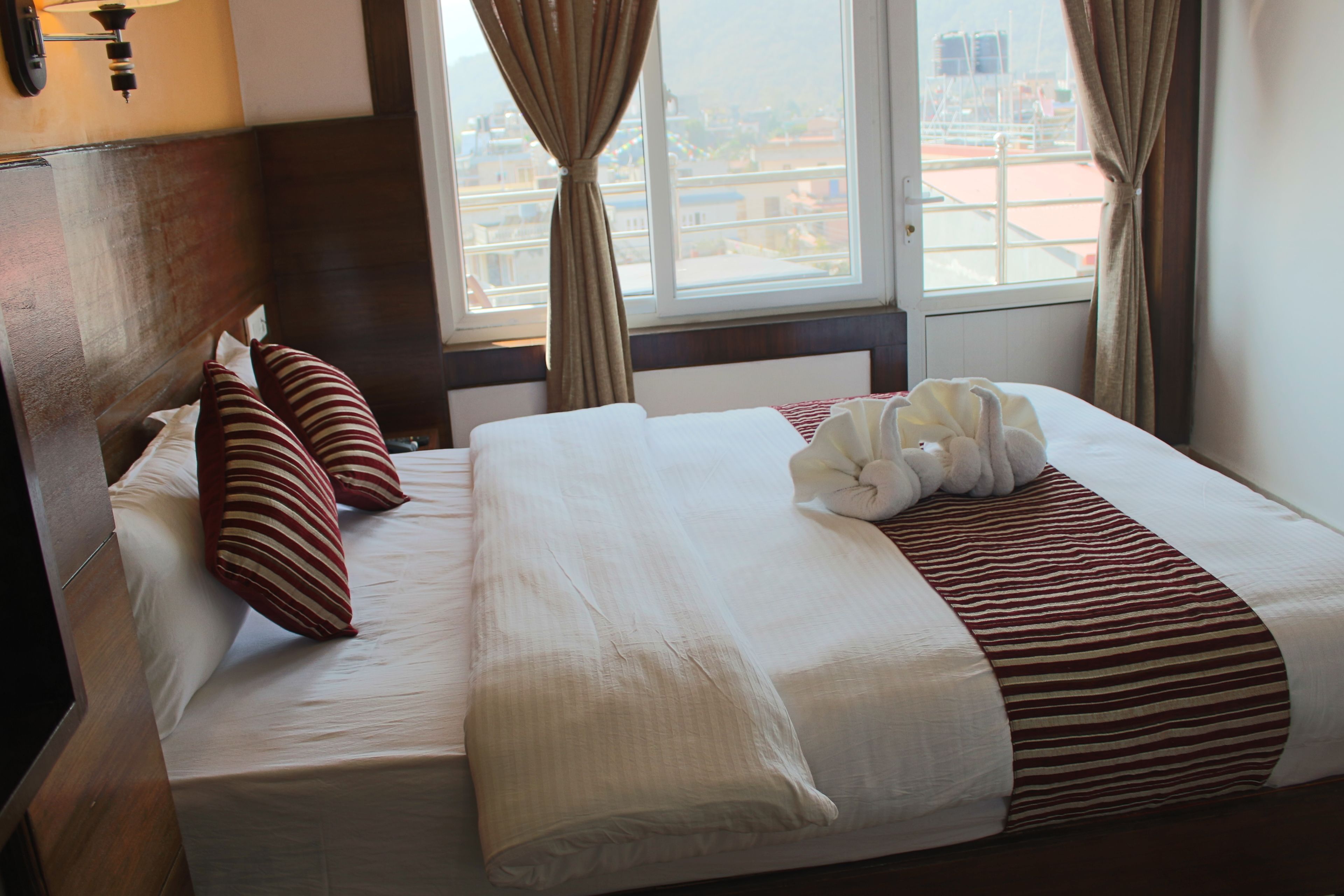 Una cama bien hecha con almohadones a rayas, una colcha blanca y un plaid a rayas.
