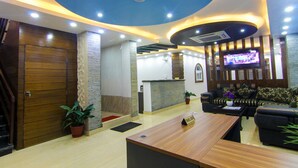 A lobby with a reception desk, seating area, and a TV screen. - Hotel Lakeside (Pokhara)
