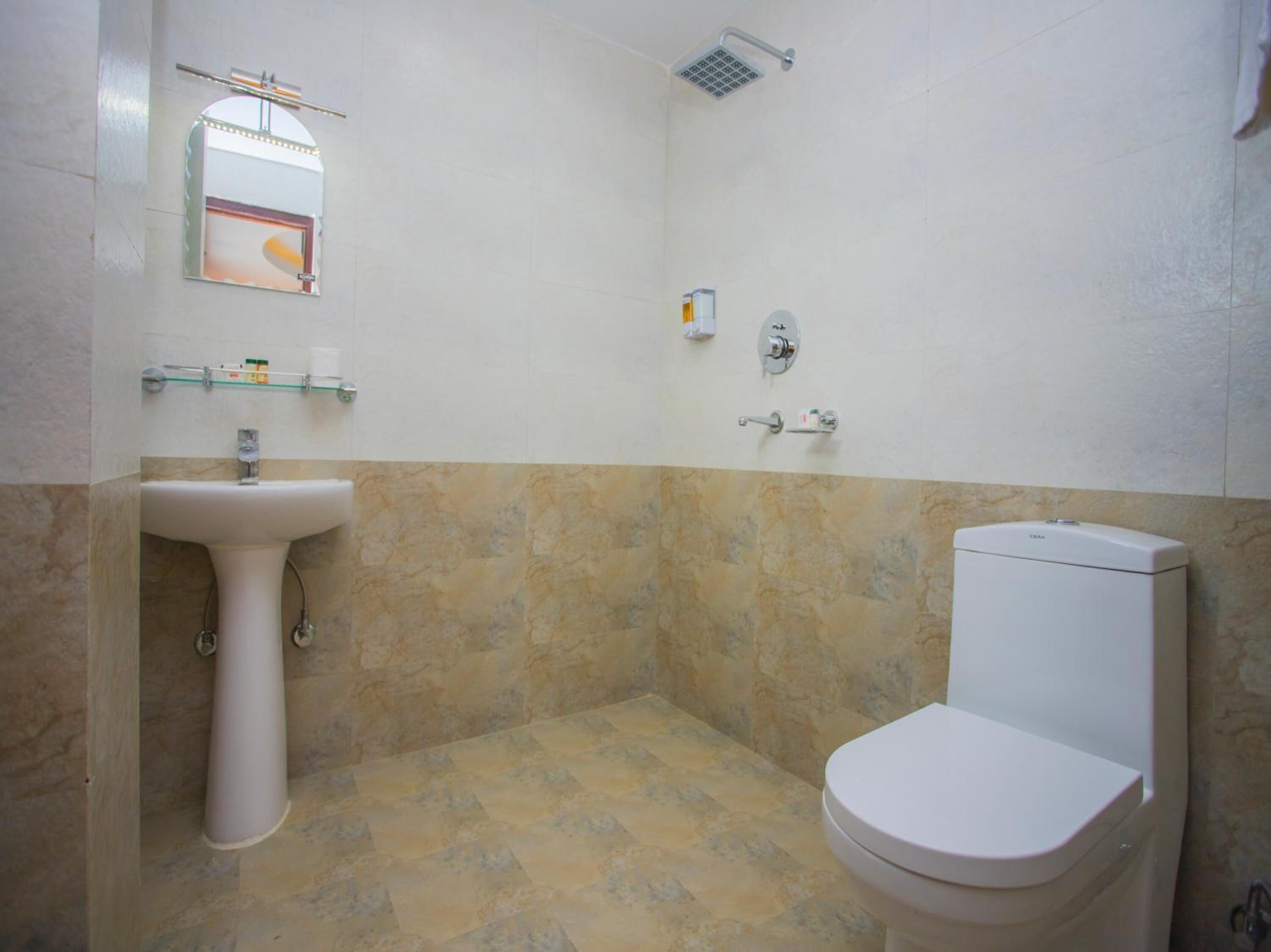 A bathroom with a sink, toilet, shower, and a mirror.