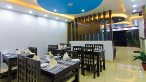 A restaurant with multiple tables and chairs, a blue ceiling, and a wooden partition. - Hotel Lakeside (Pokhara)