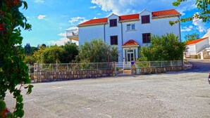 A two-story building with a red-tiled roof, a stone wall, and a gated entrance. - Above the Blue: 1BR Peaceful Horizon Pool&Terrace (Bosanka)