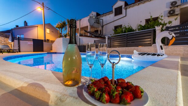 A poolside setting with a bottle, glasses, and a plate of strawberries. - Above the Blue: 1BR Peaceful Horizon Pool&Terrace (Bosanka)