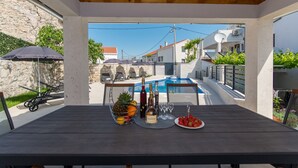A covered outdoor dining area with a pool in the background. - Above the Blue: 1BR Peaceful Horizon Pool&Terrace (Bosanka)