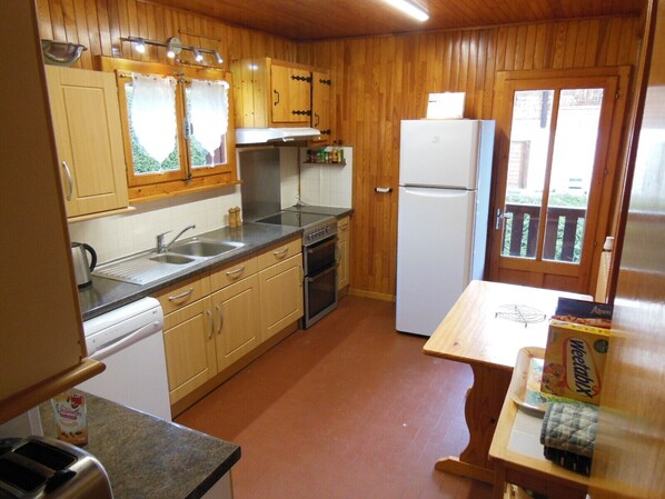 Una cocina compacta con gabinetes de madera, estufa, fregadero y refrigerador.