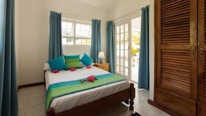 Un dormitorio con cama, cortinas, un armario de madera y una ventana.