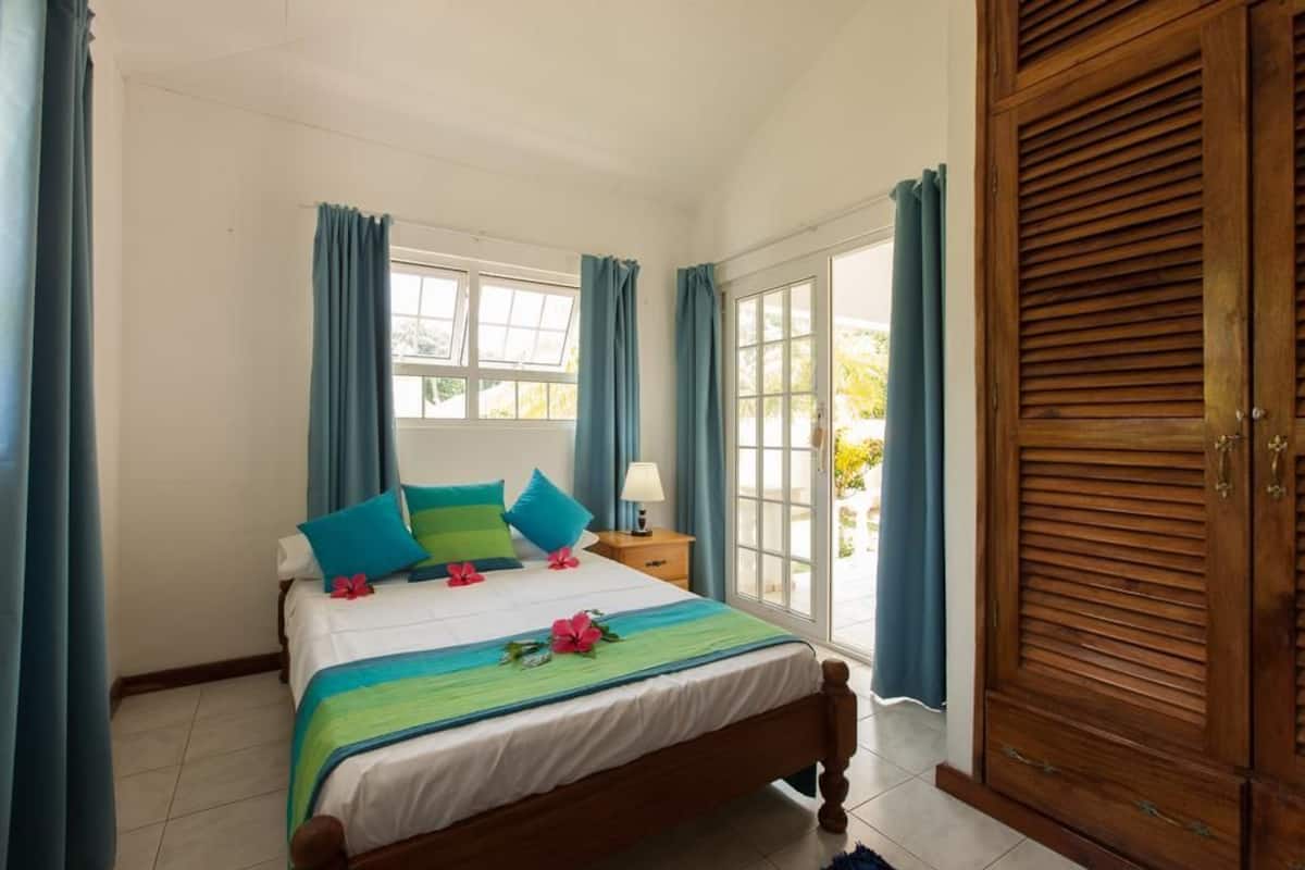 A bedroom with a bed, curtains, a wooden wardrobe, and a window.