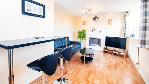 A modern living room with a bar area, a sofa, a TV, and a fireplace.