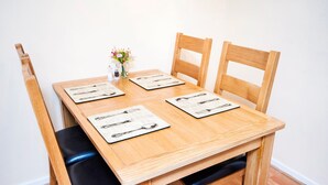 A wooden dining table with four chairs, each with a placemat featuring a black and white design.