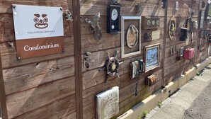 Eine Holzwand mit verschiedenen antiken Gegenständen und einem Schild mit der Aufschrift 'Villa from Okinawa Condominium'.