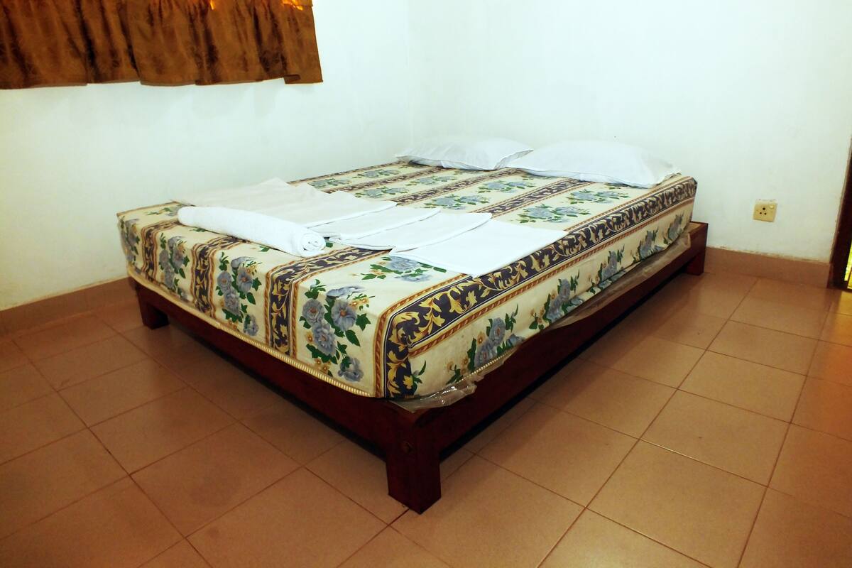 A single bed with a floral bedspread, a wooden headboard, and a white pillow.