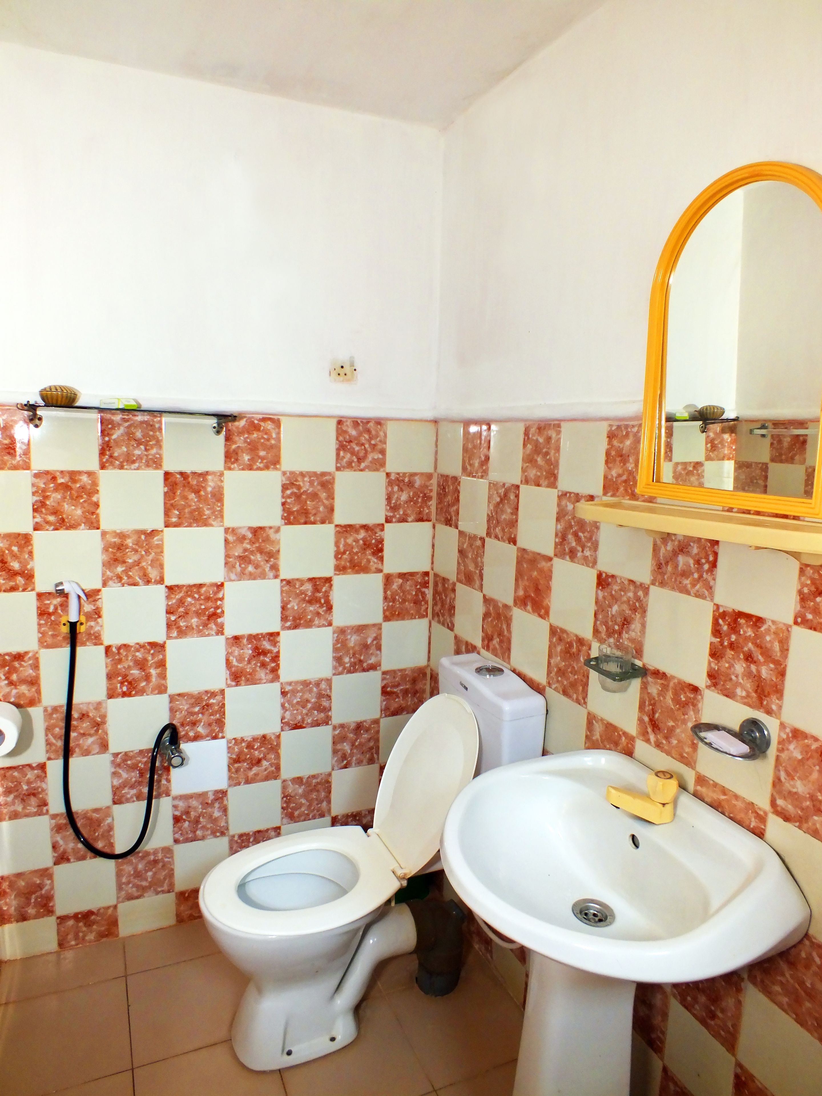 A bathroom with a toilet, bidet, sink, and a mirror on the wall.