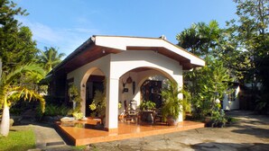 A covered outdoor seating area with stone flooring and potted plants. - River Side Villa (Galle)