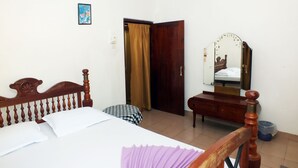 A bedroom with a bed, a wooden headboard, a ceiling fan, a bedside table, a mirror, and a door. - River Side Villa (Galle)