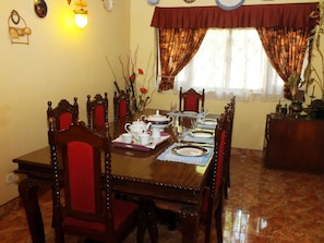 Comedor con una mesa de madera dispuesta para cuatro, rodeada de sillas con cojines rojos.