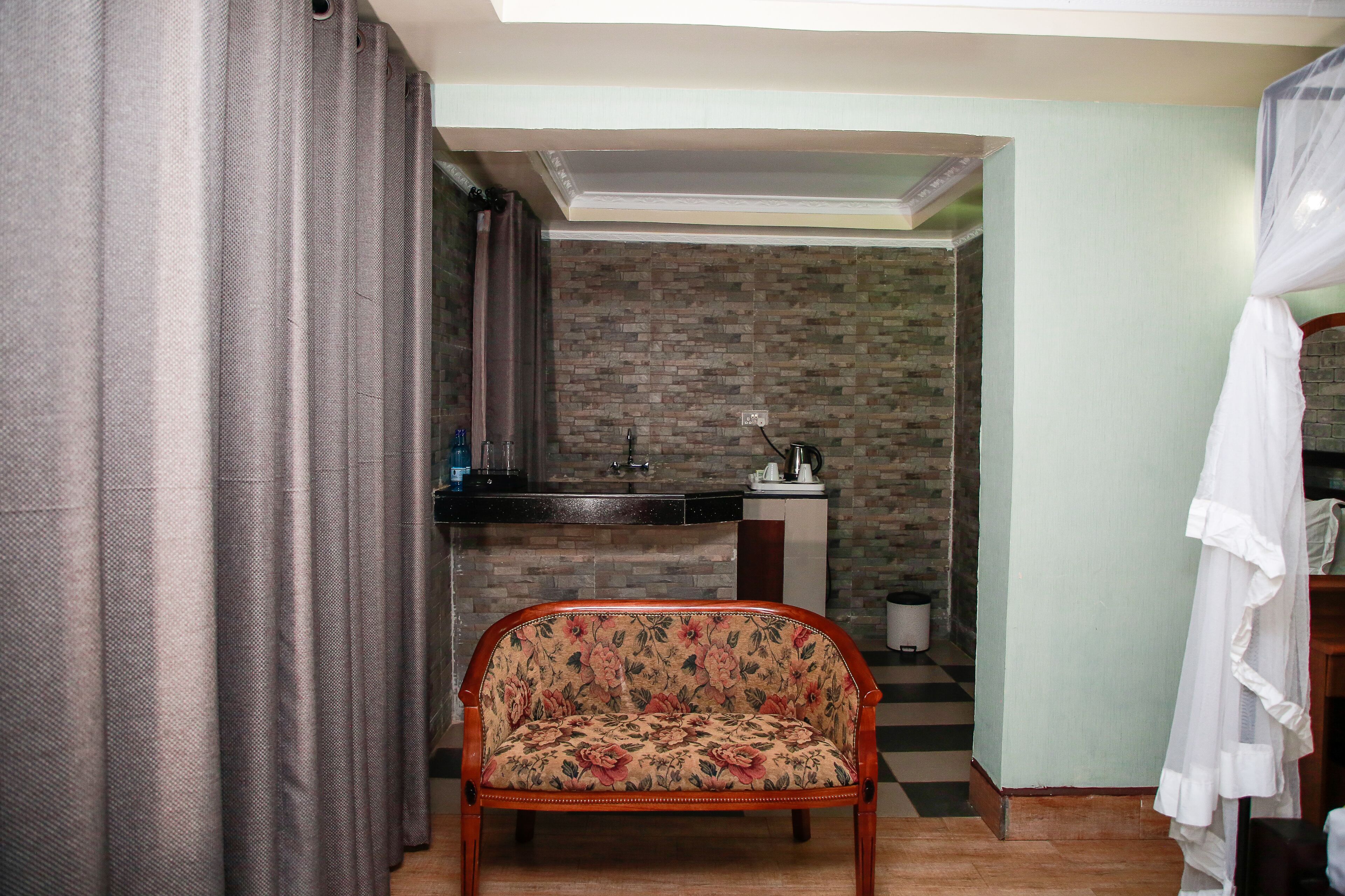 Una habitación con sofá, kitchenette pequeño, cortina y cama con dosel.
