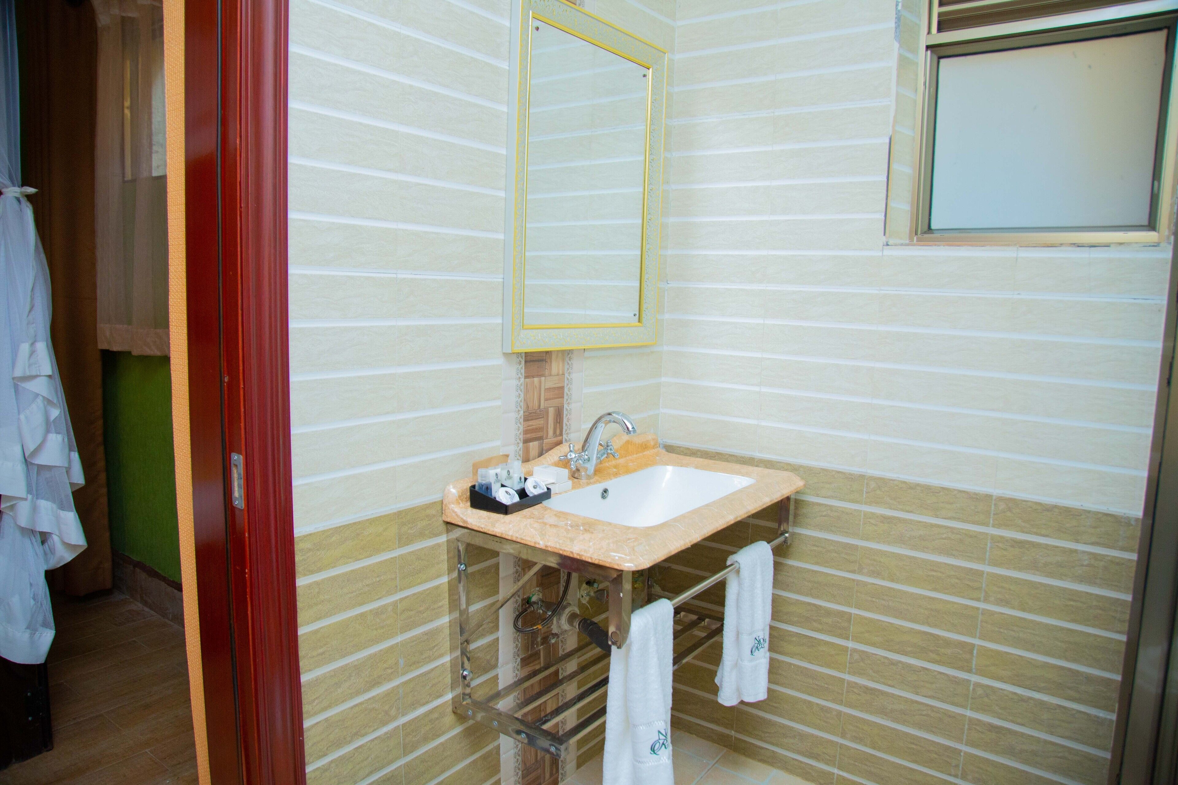 Un bagno con lavandino, specchio e portasciugamani.